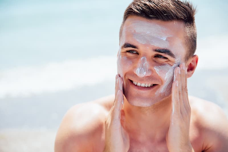 man putting on sunscreen on face